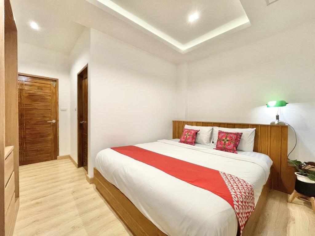 a bedroom with a large white bed with red pillows at Ashi Hostel in Chiang Mai