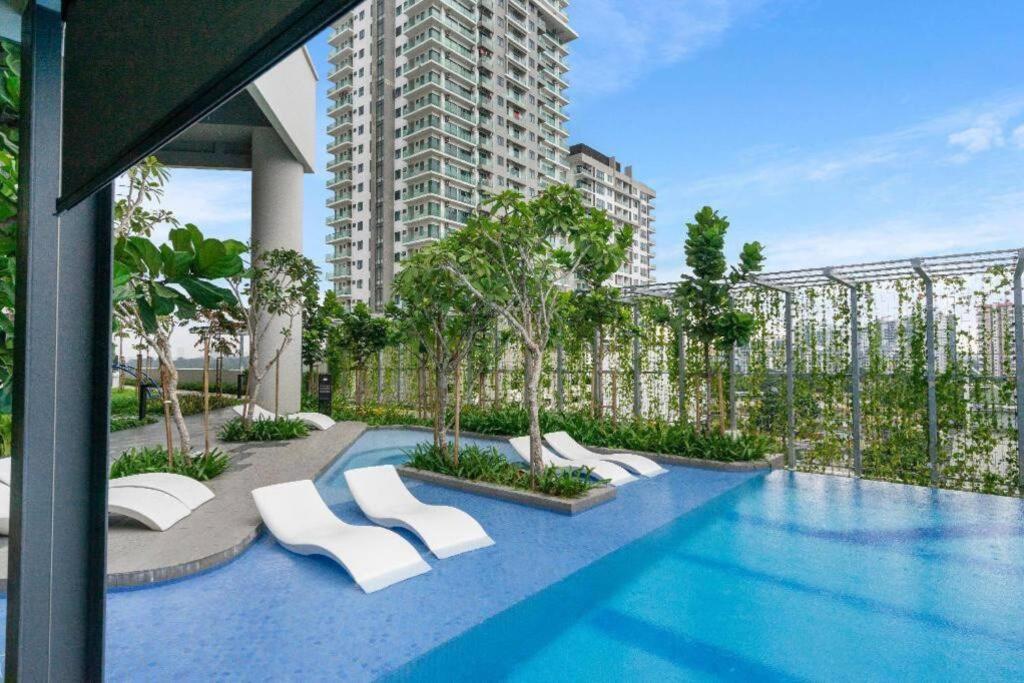 una piscina con sedie bianche e un edificio di Highpark Suites ByTheNook a Petaling Jaya