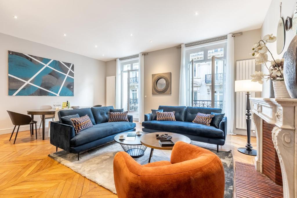ein Wohnzimmer mit blauen Sofas und einem Tisch in der Unterkunft Sweet Inn - Triangle d'Or in Paris
