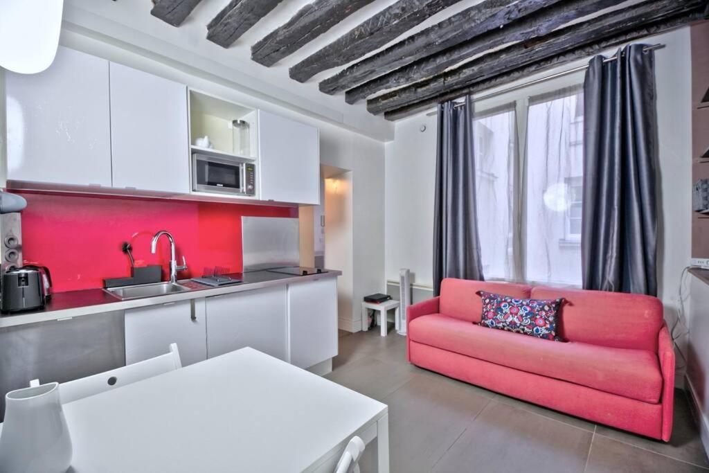 un salon avec un canapé rouge et une cuisine dans l'établissement 1 bedroom apt only 15 min walk to The Louvre, à Paris