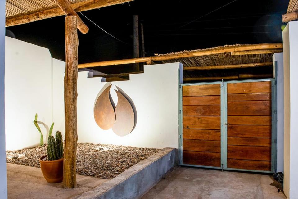 a garage with wooden doors and a cactus at Amaragua in Fiambala