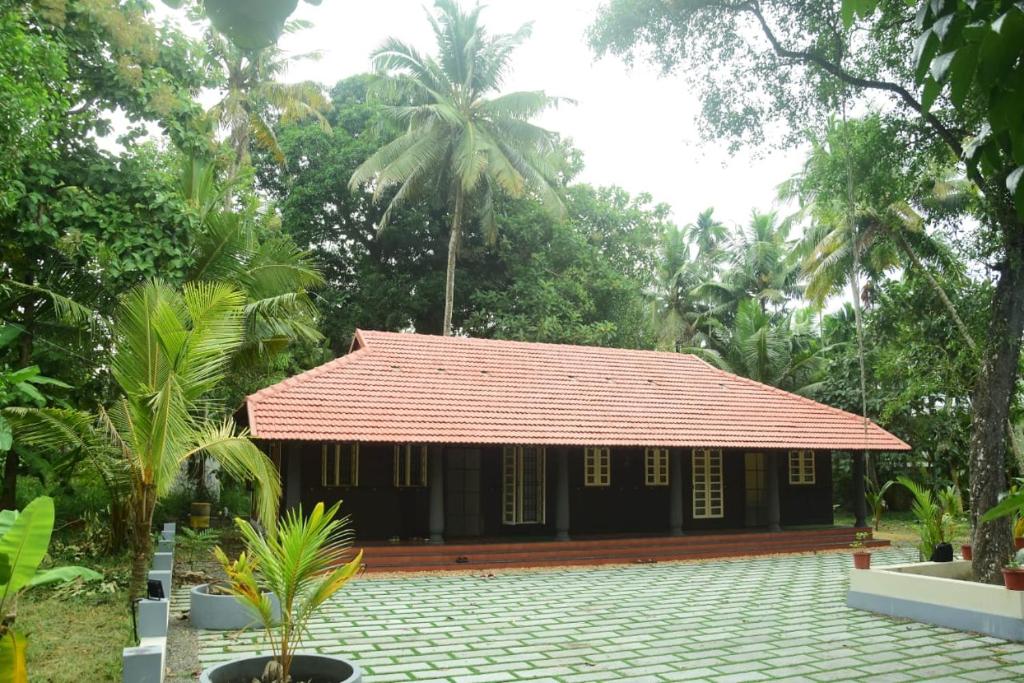 een klein huis met een rood dak in een bos bij Manjippuzha Nature Space in Alleppey