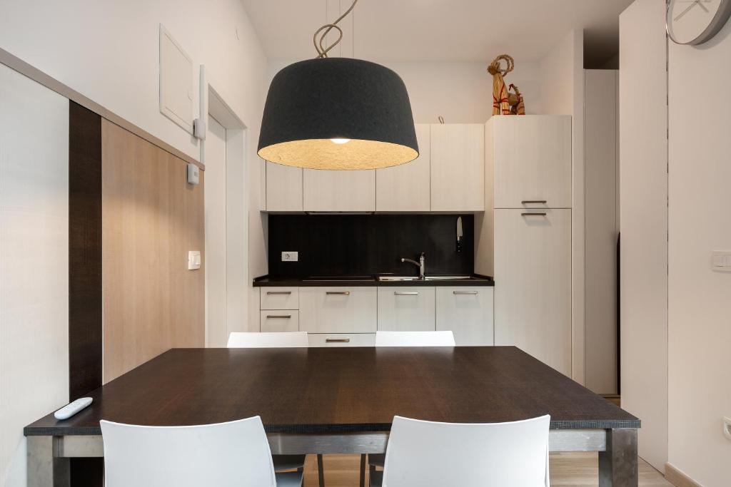 mesa de comedor con sillas blancas y lámpara negra en Apartma Juniper, en Kranjska Gora