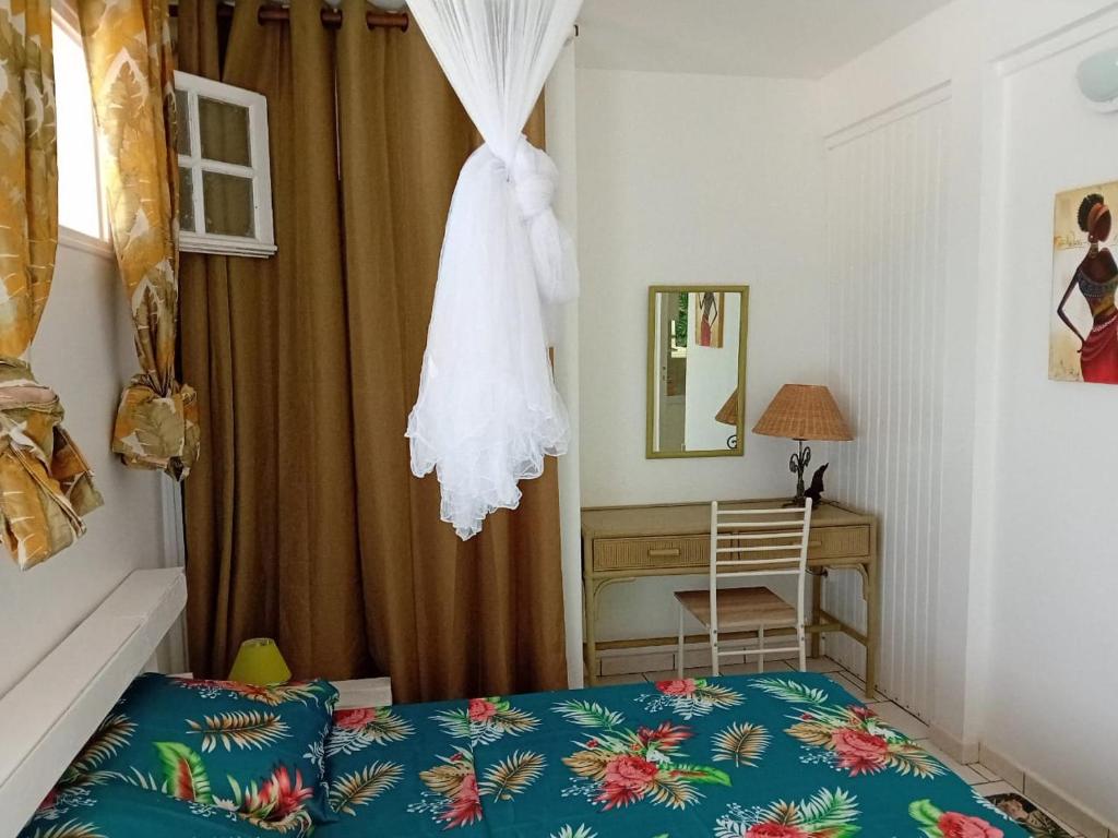 a bedroom with a bed and a desk with a mirror at Kay Anaisa in Le Morne Rouge