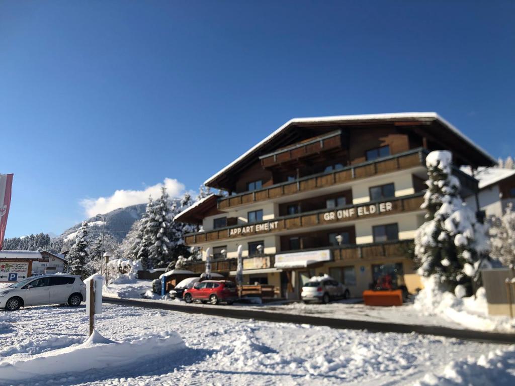 a large building with cars parked in the snow at Appartement Grünfelder in Oberperfuss