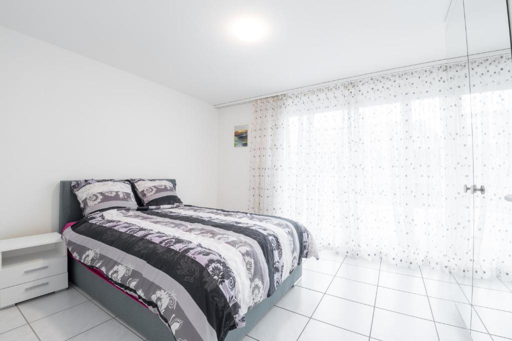 um quarto branco com uma cama e um chuveiro em 3.5 Room Apartment em Würenlos