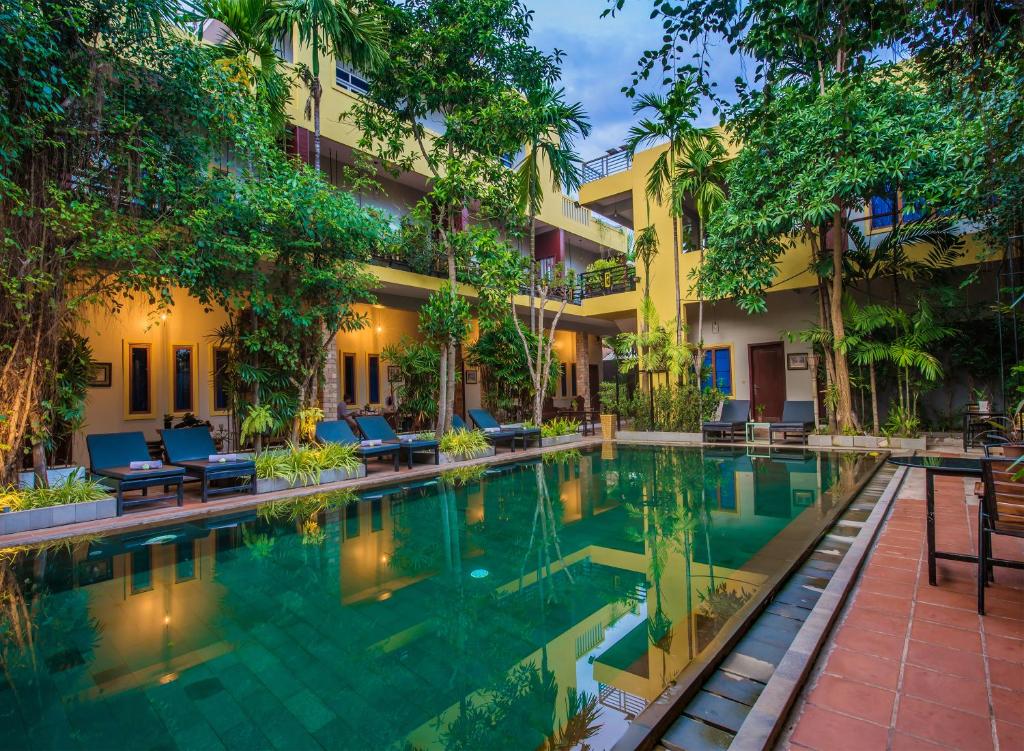 a swimming pool in front of a building with a resort at Samnak Lounge in Siem Reap