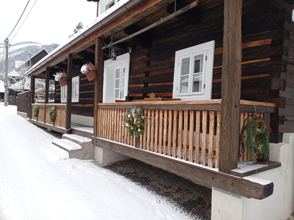 a log cabin with white windows and snow at Chalupa Bocza in Nižná Boca