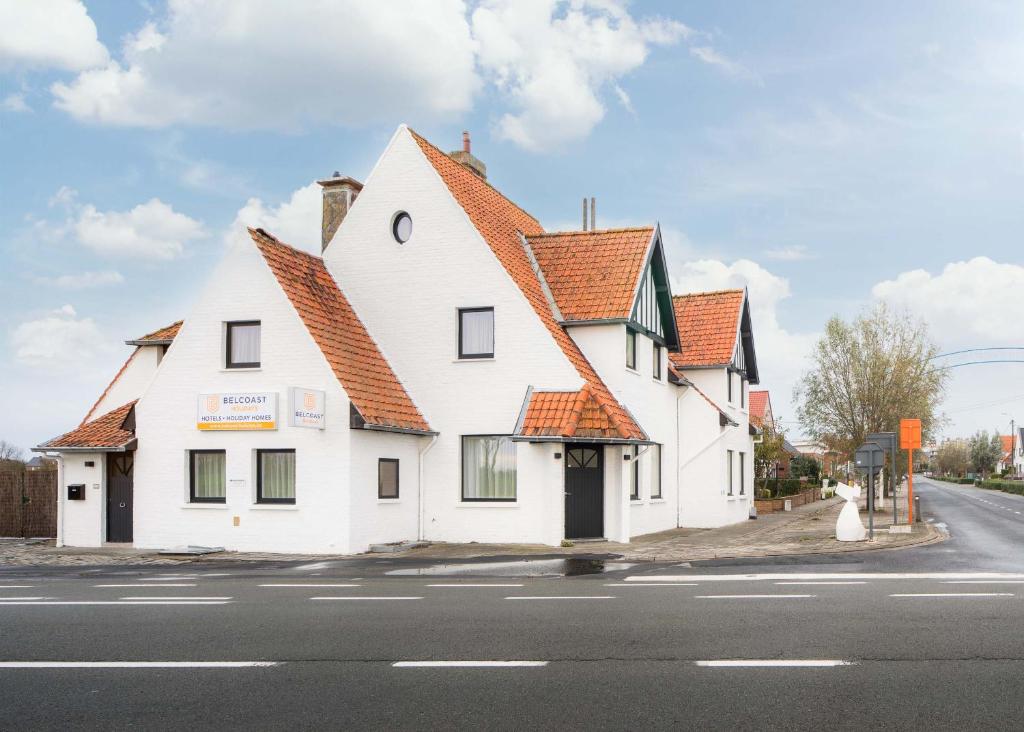a white building with an orange roof on a street at Belcoast Guesthouse in Middelkerke