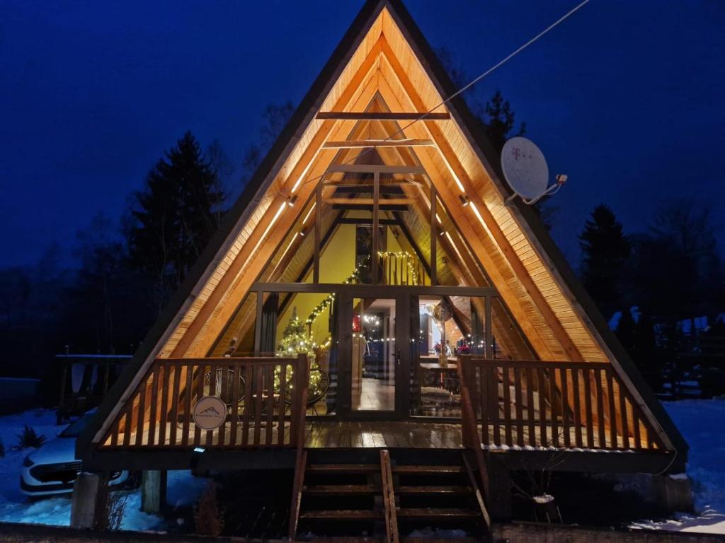 a frame cabin with a lit up window at night at Harmony Villa Lupeni Straja in Lupeni