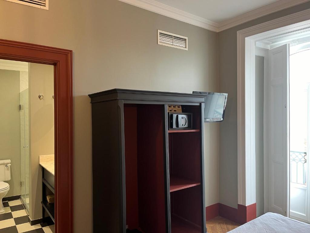 a room with a cabinet with a microwave on it at Pensao Londres in Lisbon