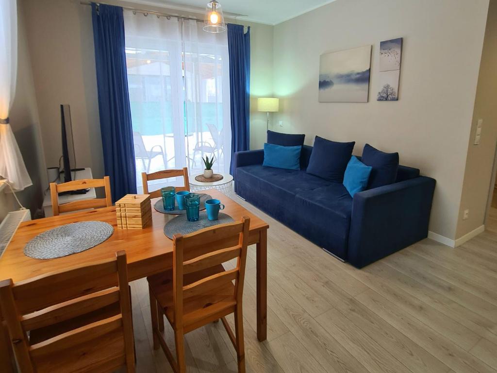 uma sala de estar com um sofá azul e uma mesa em APARTAMENTY "LA VILLA" SUPERIOR III z prywatnym ogrodem, tarasem i parkingiem em Kudowa-Zdrój
