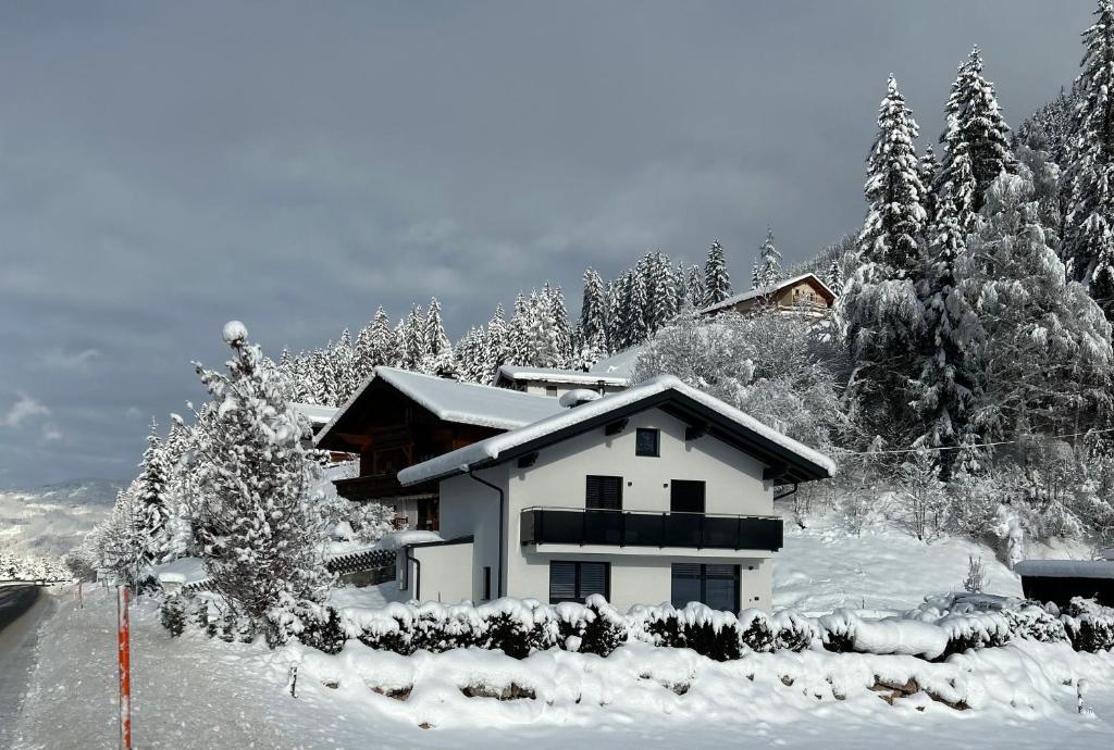 a house covered in snow in front of trees at My Appartements in Untertauern