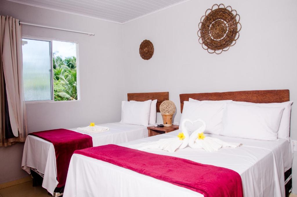 um quarto com 2 camas com lençóis vermelhos e brancos em Pousada Chalés do Toque em São Miguel dos Milagres