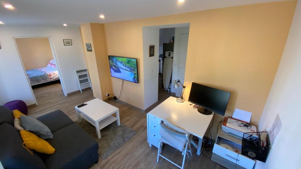 a living room with a couch and a desk with a television at Modern and well done flat Geneva - self check-in in Saint-Genis-Pouilly