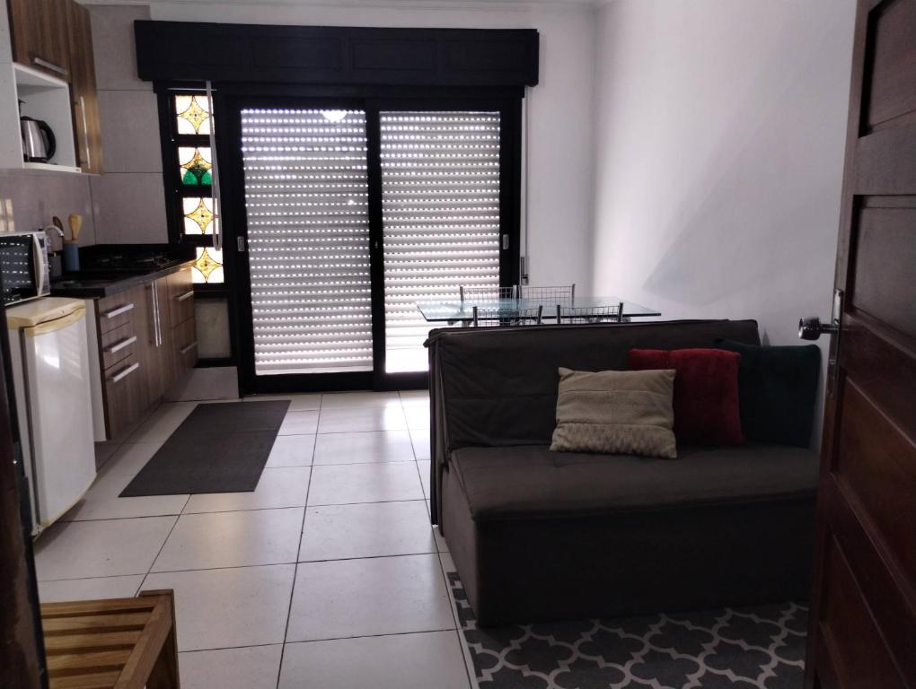 a living room with a couch and a kitchen at Hostap de frente com sacada in Porto Alegre