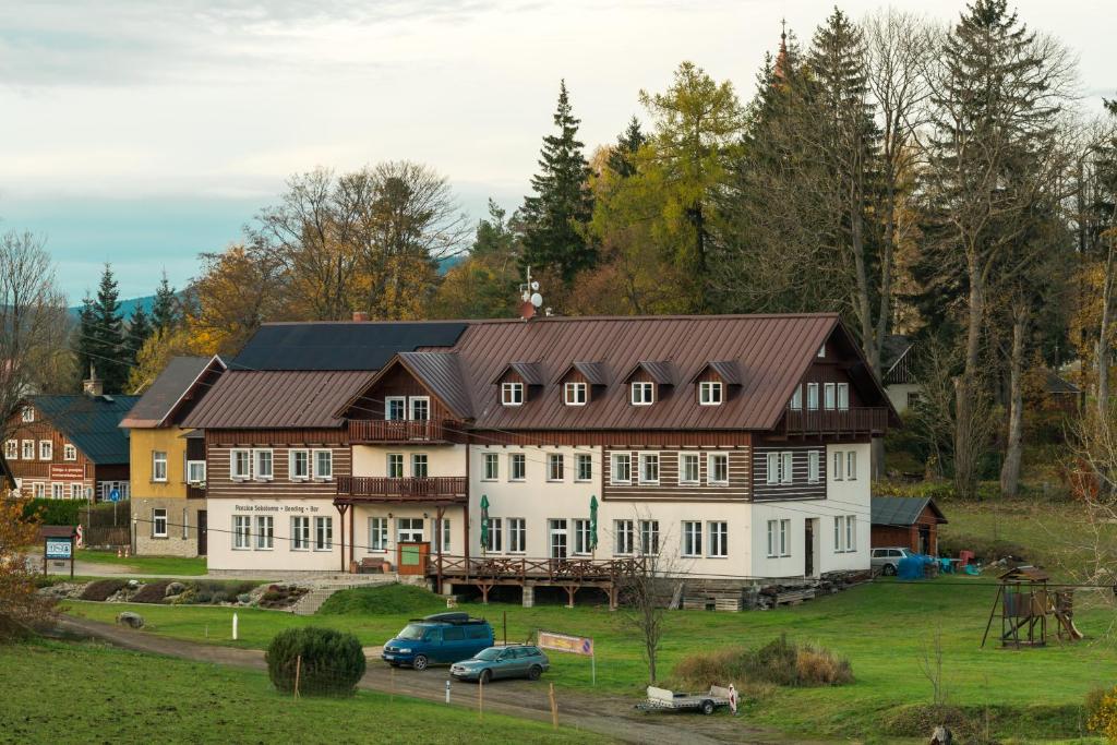 ein großes weißes Haus mit braunem Dach in der Unterkunft Penzion Sokolovna in Kořenov