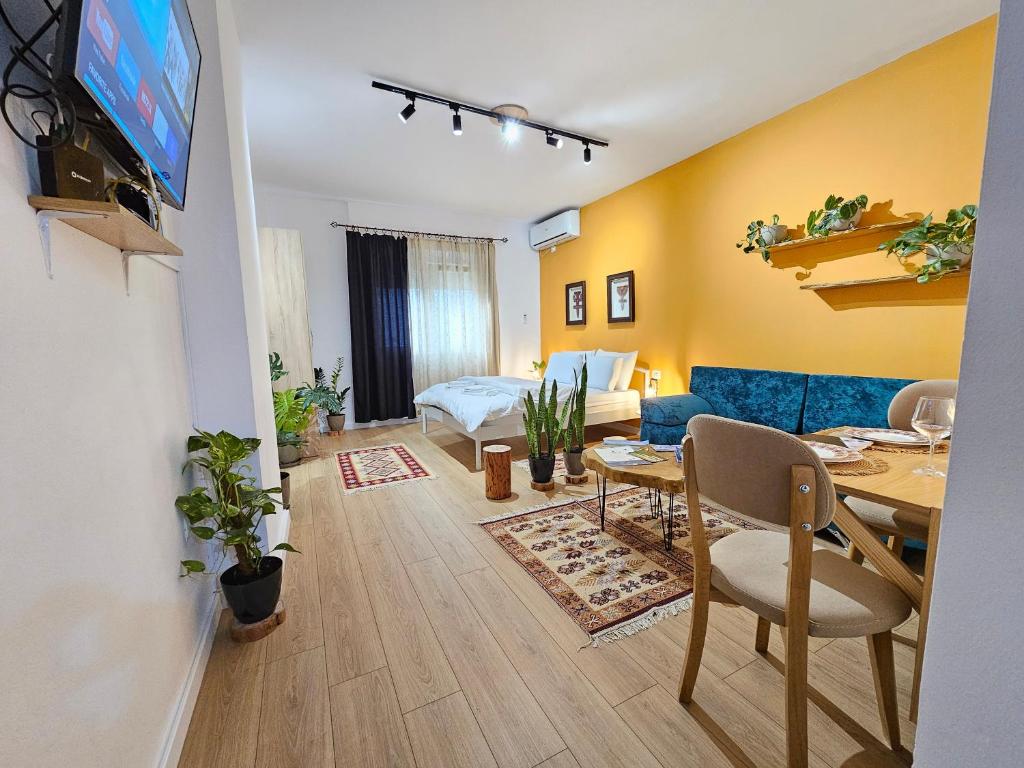 ein Wohnzimmer mit einem Esstisch und ein Wohnzimmer mit gelben Wänden in der Unterkunft Vibe Studio Apartment in Tirana