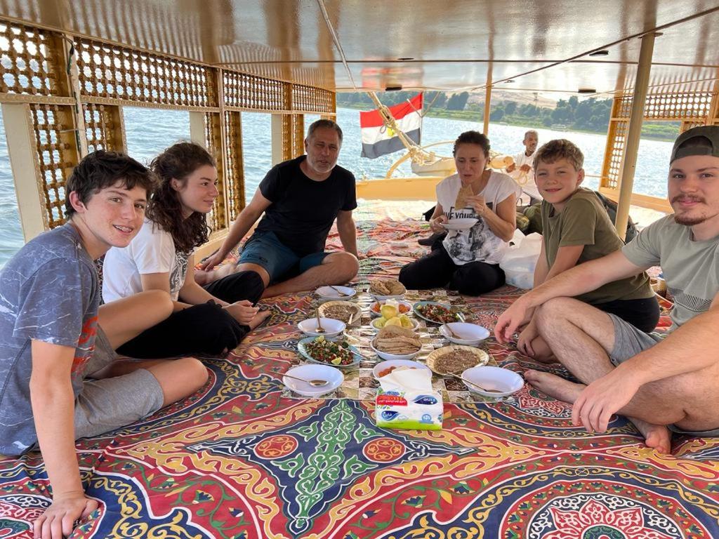 un grupo de personas sentadas en un barco comiendo comida en Nile Felucca Adventure, en Asuán