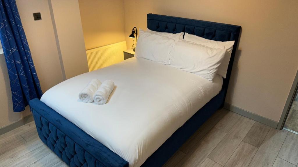 a bed with a blue headboard and white sheets and pillows at One Bedroom Apartment in Walsall Sleeps 4 FREE WIFI By Villazu in Bloxwich