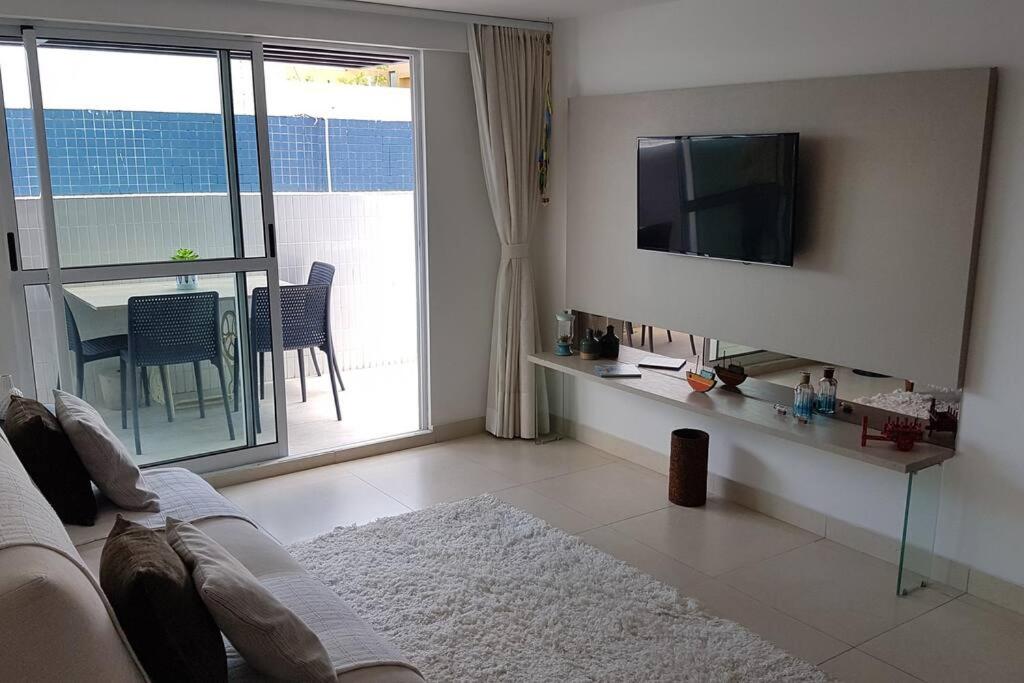 uma sala de estar com um sofá e uma televisão na parede em Aconchegante Apartamento Beira-Mar (Ampla Varanda) em João Pessoa