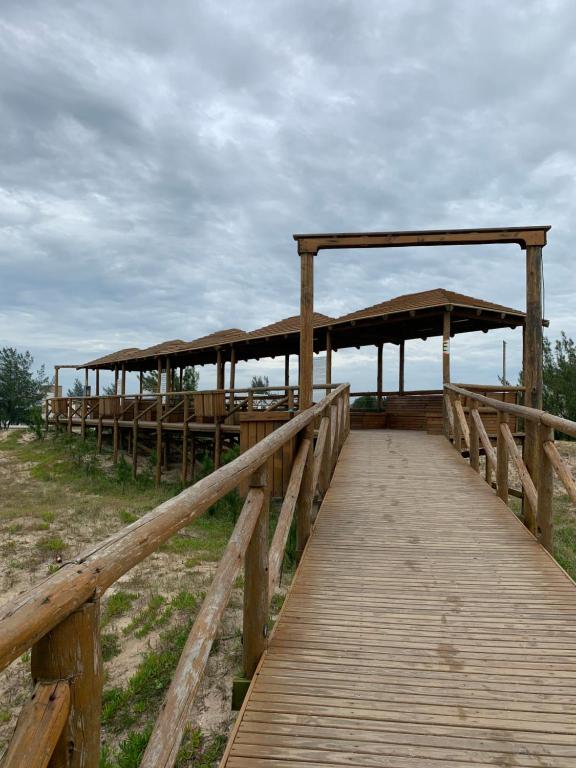 una passerella di legno con ombrelloni sulla spiaggia di Edícula aconchegante 100m do Mar a Sombrio