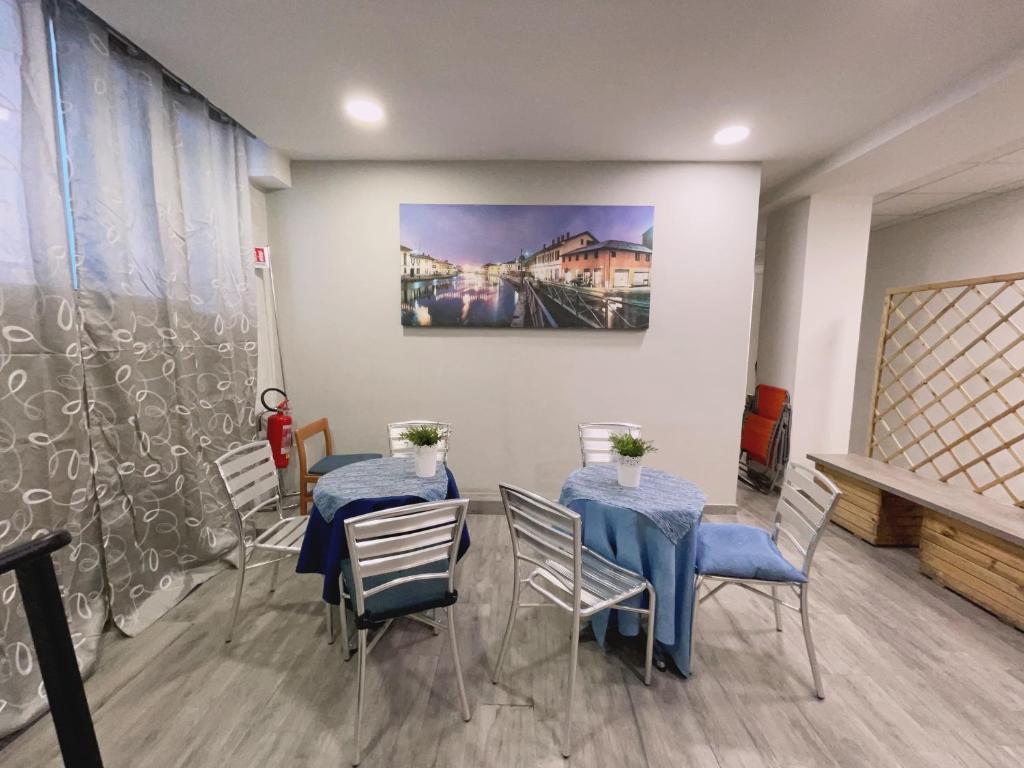 un comedor con 2 mesas y sillas y una pintura en HOTEL BISSI, en Milán