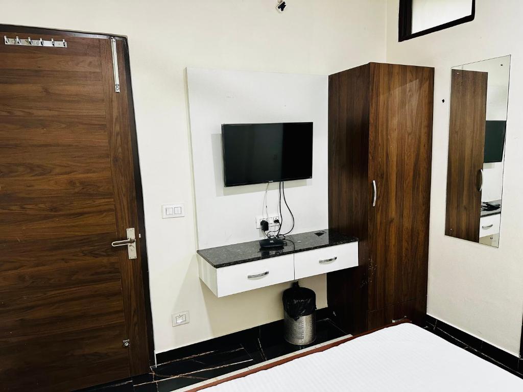 Pokój z telewizorem na ścianie z drzwiami w obiekcie grover international w mieście Bathinda