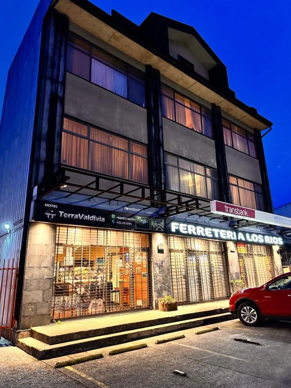 Un edificio con un coche rojo aparcado delante. en Apart hotel Terra Valdivia, en Valdivia
