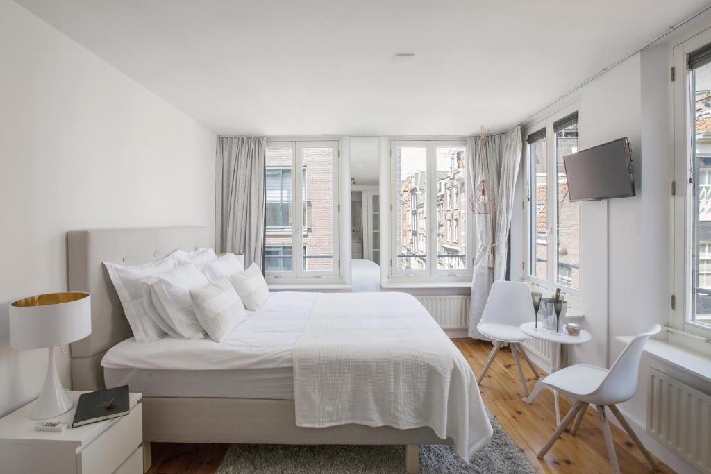 a white bedroom with a white bed and windows at Jordaan Suite bed and bubbles in Amsterdam