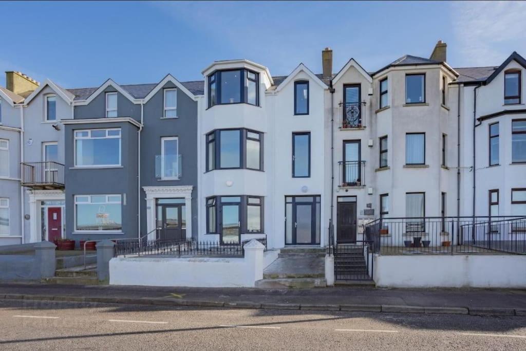 a large white building with black windows on a street at Modern appartment with sea views in Portrush