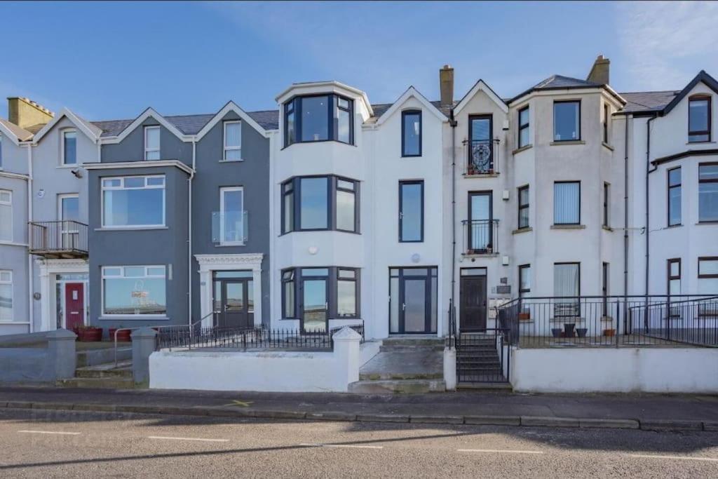 a large white building with black windows on a street at Modern apartment with sea views in Portrush
