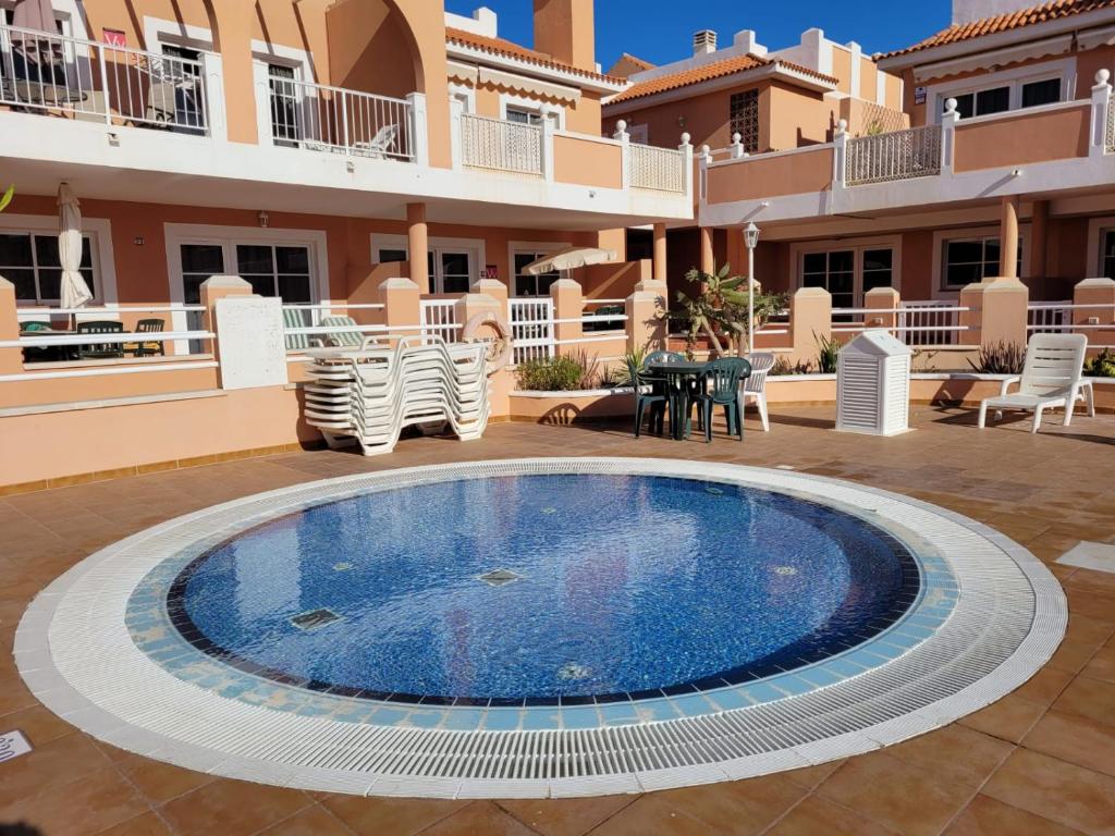 a swimming pool in the middle of a courtyard with a house at Apartamento funcional en residencial con piscina en inmejorable ubicación en centro de la isla in Caleta De Fuste