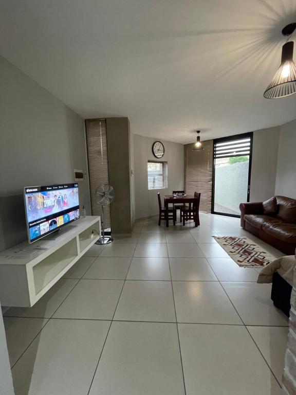 sala de estar con TV de pantalla plana y sofá en Wild olive B, en Windhoek