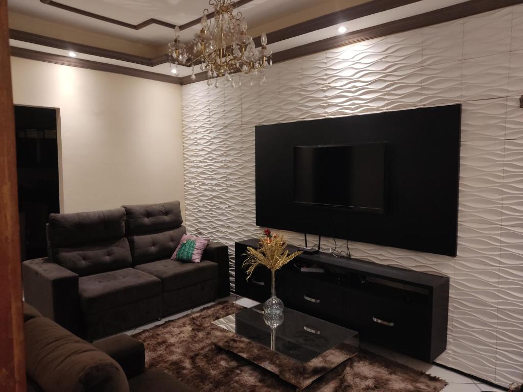 uma sala de estar com um sofá e uma televisão de ecrã plano em House beach em Camocim