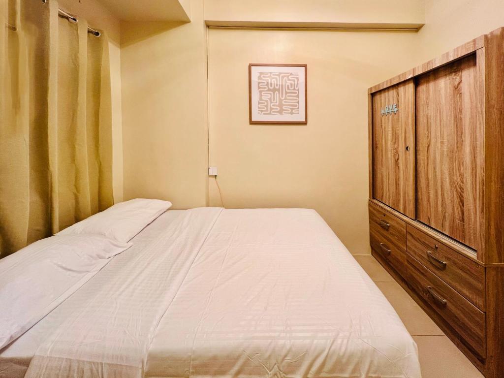 a bedroom with a bed and a wooden cabinet at * * Y Stylish 2BR Option for 6 in Iloilo City