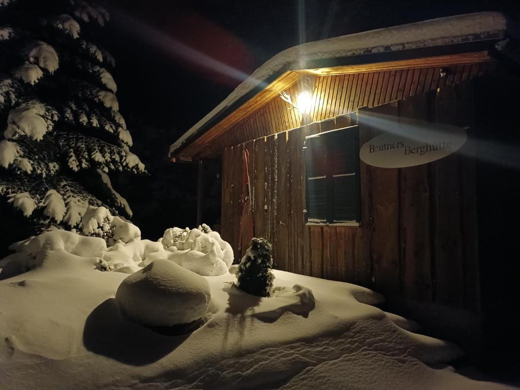 een met sneeuw bedekte hut met een kerstboom ervoor bij Beutners Berghütte in Stützerbach