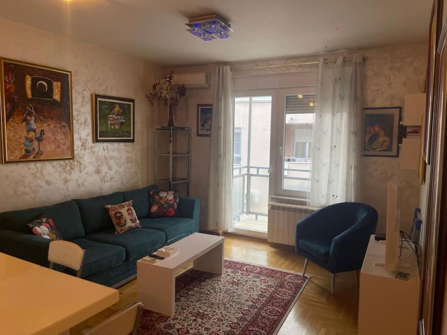 sala de estar con sofá azul y ventana en Art-Inspired, Cozy Apartment en Vračar (historical)