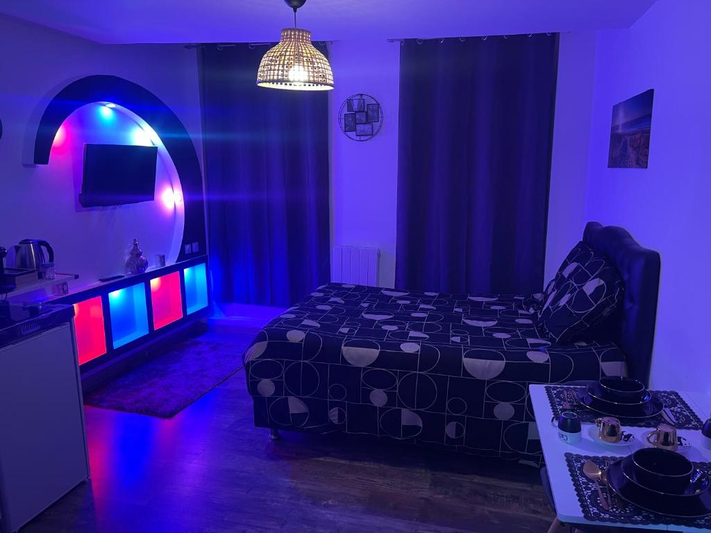 a bedroom with a bed and a room with purple and pink lights at Le cocon du Nil jolie studio in Douai