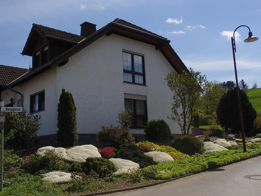 ein weißes Haus mit Felsen davor in der Unterkunft Ferienwohnung Meisenthal nähe Nürburgring in Kelberg