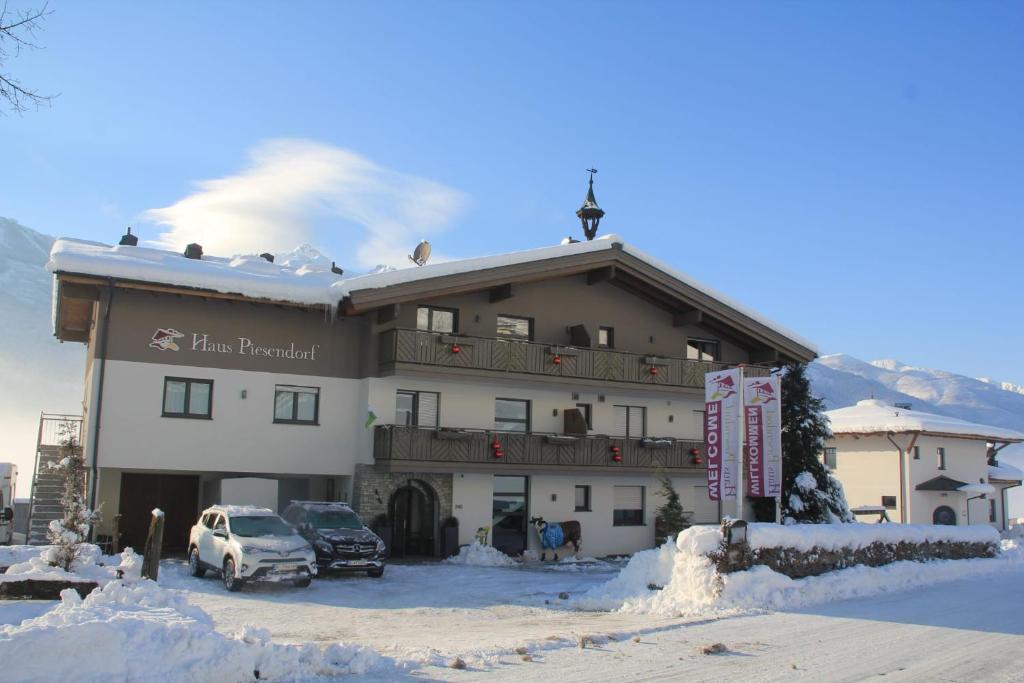 ein großes Gebäude mit Autos im Schnee in der Unterkunft Haus Piesendorf in Piesendorf