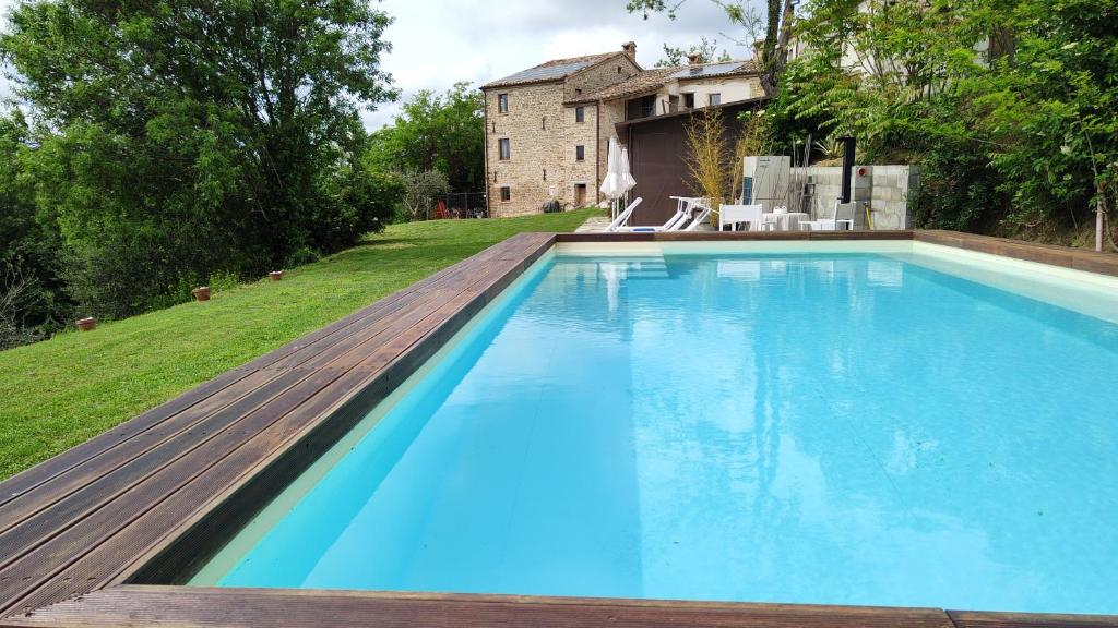 uma grande piscina com um deque de madeira ao lado de uma casa em Borgo Calbianco - Private House with Pool & AirCo em Cereto