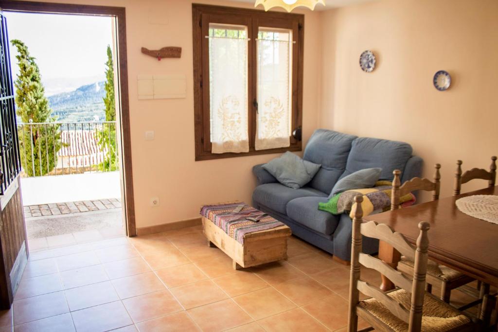 Casa rural El Cestero في Castellote: غرفة معيشة مع أريكة زرقاء وطاولة