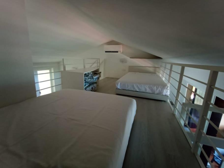 een witte slaapkamer met 2 bedden en een trap bij Open space fronte lago in Monte Isola