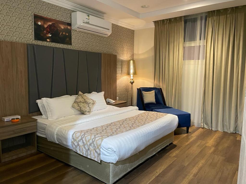 Habitación de hotel con cama y silla azul en سكون سويت للشقق الفندقية en Hail