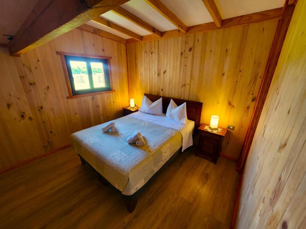 um quarto com uma cama num chalé de madeira em Cabaña Alto Naupe em Puerto Saavedra