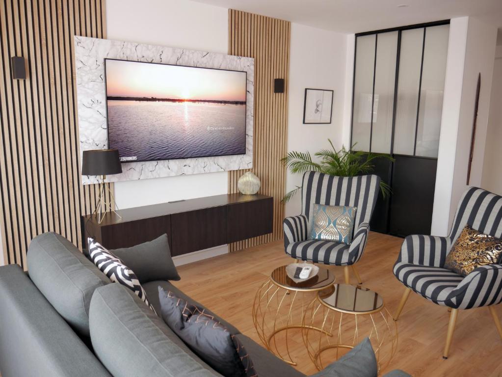 a living room with a couch and two chairs and a tv at Le Penthouse des Halles in Perpignan