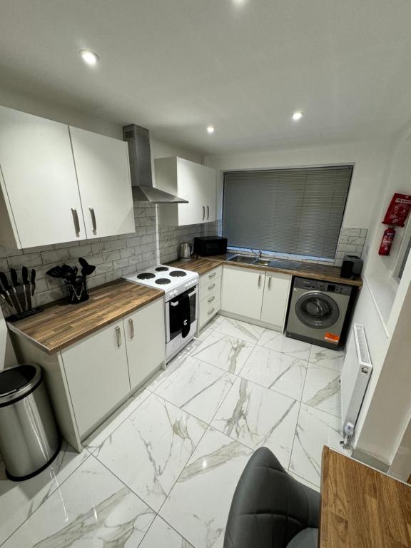 eine Küche mit weißen Schränken und Marmorböden in der Unterkunft Luxary private detached property in Brettell Lane