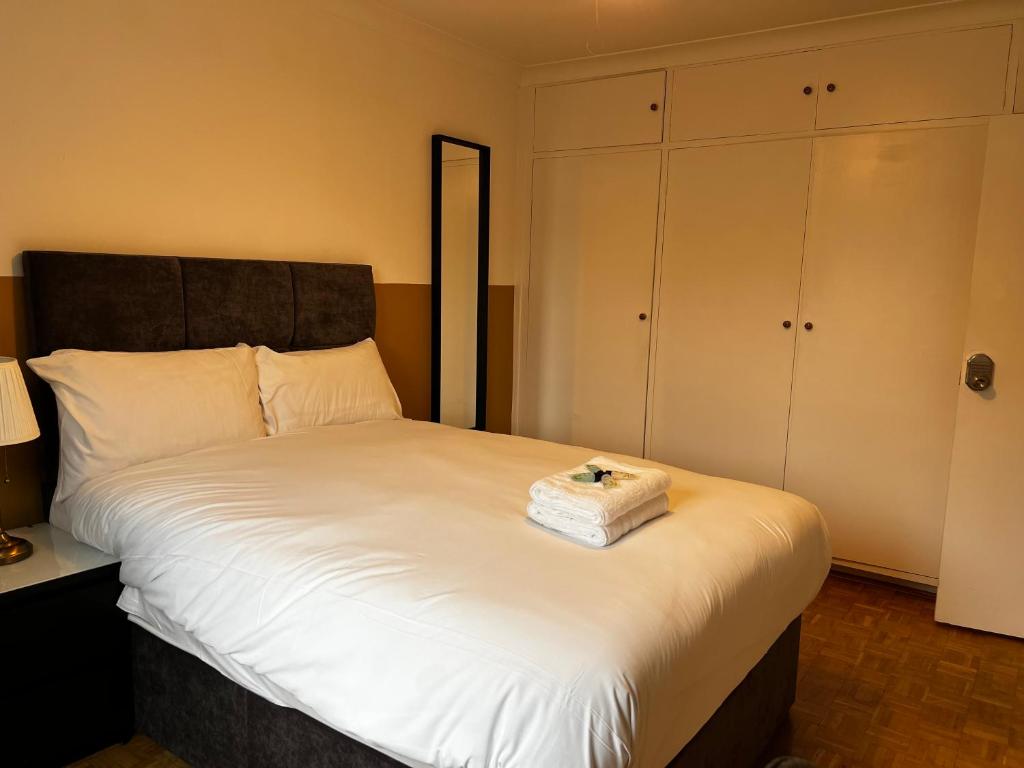 1 dormitorio con 1 cama blanca grande y cabecero negro en Dartford Stay, en Kent