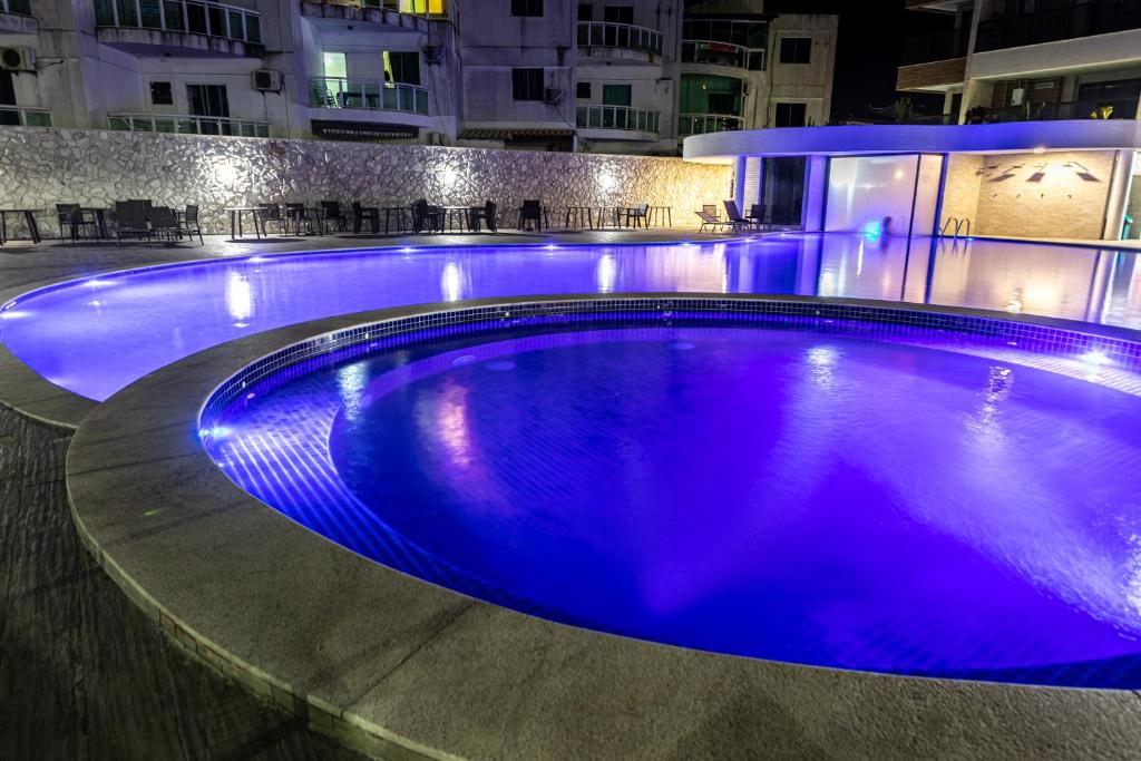 a large swimming pool at night with blue lights at Apto à beira-mar em Arraial do Cabo in Arraial do Cabo